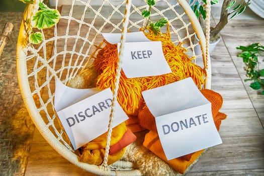 Signs with the words keep, donate, discard and fashion clothes folded in stacks in cozy room. The concept of cluttering and decluttering. Background