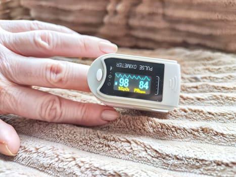 Close up of hand with a pulse oximeter on the finger.