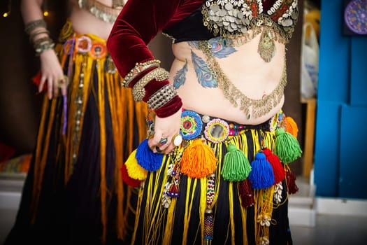 Diverse group of women wearing vibrant, multi-colored dress and tassels dancing tribal on ethnic celebratory event