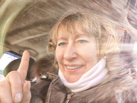 A woman in a car taking a selfie while enjoying a drive. Female driver posing inside car and the rays of the sun in the background