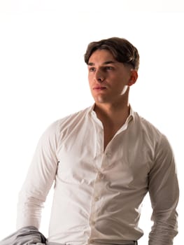 A man dressed in a white shirt is striking a pose for a photograph. He appears confident and poised as he smiles for the camera, showcasing his outfit.