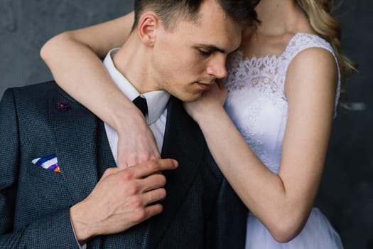 Cute wedding couple in the interior of a classic studio decorated. They kiss and hug each other.