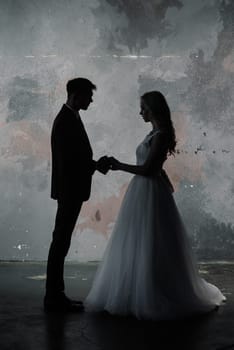 Cute wedding couple in the interior of a classic studio decorated. They kiss and hug each other.