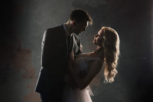 Cute wedding couple in the interior of a classic studio. They kiss and hug each other.