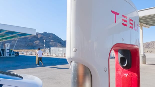 Baker, California, USA-December 3, 2022-During the day, a Tesla vehicle is seen charging at a Tesla Supercharging station, utilizing the high-speed charging infrastructure for convenient and efficient electric vehicle refueling.