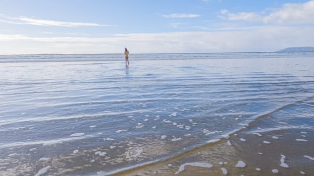 Little girl, braving the cold, joyfully runs in her swimsuit across the beach during winter.