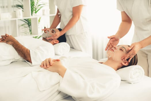Serene modern daylight ambiance of spa salon, couple customer indulges in rejuvenating with facial skincare mask. Facial skin treatment and beauty cosmetology procedure for face. Quiescent