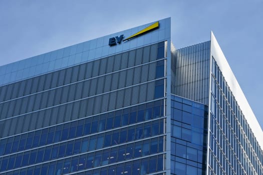 London, United Kingdom - February 03, 2019: Blue and yellow EY signage at top of their offices in Canary Wharf. Ernst & Young is UK professional services company, one of big 4 accounting firms