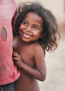 Ranohira, Madagascar - April 29, 2019: Unknown little African boy standing behind taller kid, smiling. People in Madagascar, especially Malagasy children are poor but cheerful.