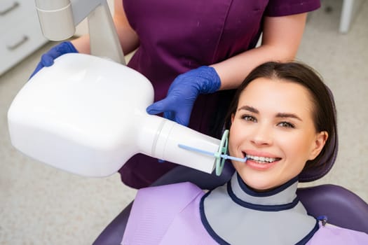 The dental assistant employs specialized tools to help the patient prepare for an X-ray procedure in the clinic.