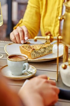 Woman enjoying savory cheese and spinach quiche with cup of aromatic espresso during friendly meeting at table in cozy cafe, cropped image