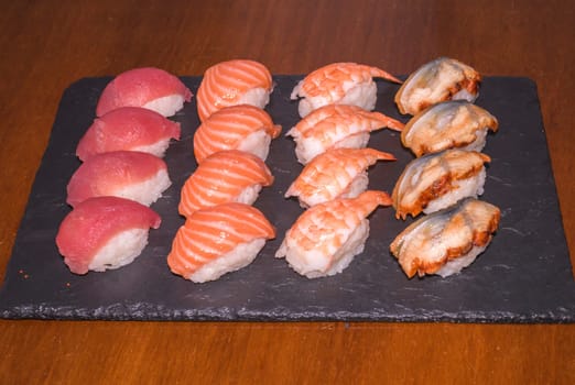 Various sushi served on black plate. Japanese food,