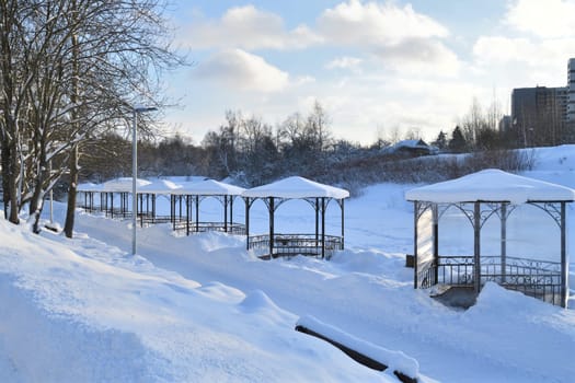 Row of metal gazebos on a bank of frozen pond, Russia