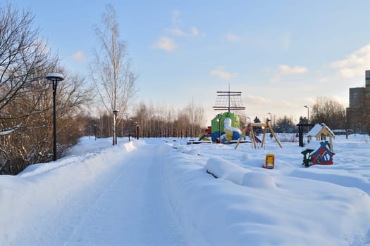 snow covered swing and slide at playground in a winter