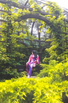 girl in a colored kimono among green thickets , spring walk