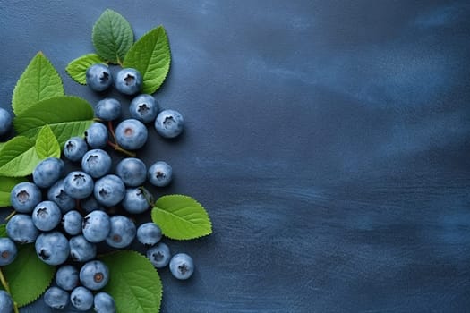 Fresh blueberries with leaves on a blue textured background.