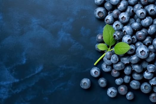 Fresh blueberries with green leaves on dark background.