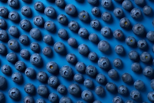 An array of ripe blueberries on a blue background.