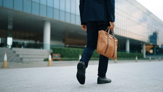 Closeup of skilled business man leg walking while holding bag. Cropped image of project manager focus on leg. Traveling, moving, journey, getting a new position, job changing. Back view. Exultant.
