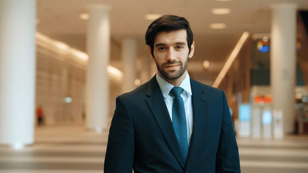 Closeup portrait of professional business man looking at camera while standing with blurred background. Manager project wear suit and smiling at camera. Caucasian investor pose at camera. Exultant.