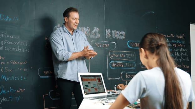 Happy caucasian teacher clap hands to applause student to encourage coding or programing prompt. Diverse student clapping hands to celebrate successful project while attend in STEM class. Edification.