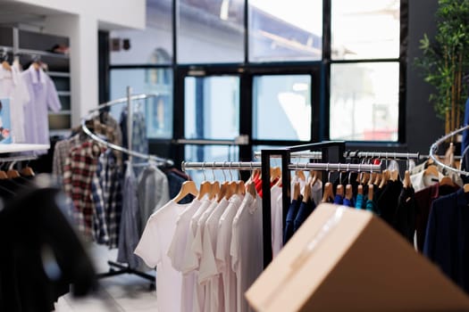 Interior of modern fashion store with stylish clothes on racks, fashionable brand design and formal wear in boutique. Empty clothing showroom in shopping mall with elegant merchandise.