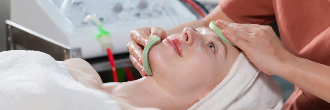 Attractive caucasian woman receive electrical facial treatment. Beautiful girl lies on spa bed while having medical treatment from professional doctor from medical spa center. Tranquility.