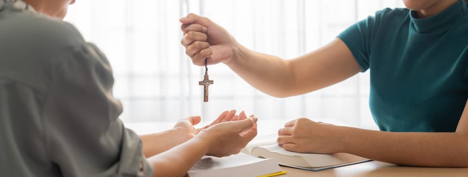 Close-up women prayer deliver holy bible book and holy cross to young believer. Spreading religion symbol. Concept of hope, religion, christianity and god blessing. Warm background. Burgeoning.