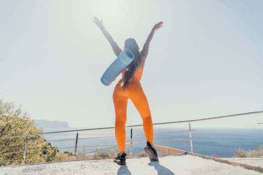 Fitness woman sea. Outdoor workout on yoga mat in park near to ocean beach. Female fitness pilates yoga routine concept. Healthy lifestyle. Happy fit woman exercising with rubber band in park.