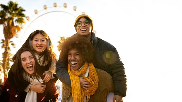 Group of diverse and multi-ethnic cheerful happy friends smiling at camera having fun outdoors. Piggy back ride. Copy space. Lifestyle concept.