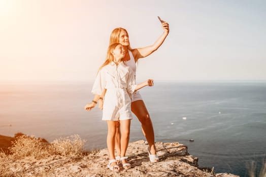 Close up portrait of mom and her teenage daughter hugging and smiling together over sunset sea view. Beautiful woman relaxing with her child.