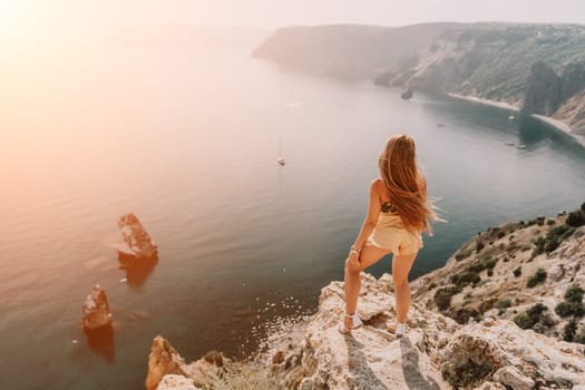 Woman travel sea. Happy tourist taking picture outdoors for memories. Woman traveler looks at the edge of the cliff on the sea bay of mountains, sharing travel adventure journey.