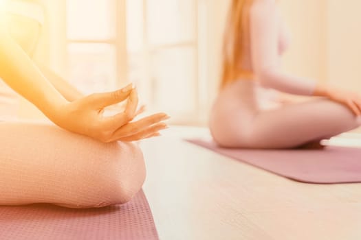 Young woman with long hair in white swimsuit and boho style braclets practicing outdoors on yoga mat by the sea on a sunset. Women's yoga fitness routine. Healthy lifestyle, harmony and meditation