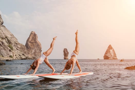 Woman sup yoga. Middle age sporty woman practising yoga pilates on paddle sup surfboard. Female stretching doing workout on sea water. Modern individual hipster outdoor summer sport activity