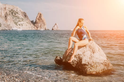 Woman travel sea. Young Happy woman in a long red dress posing on a beach near the sea on background of volcanic rocks, like in Iceland, sharing travel adventure journey