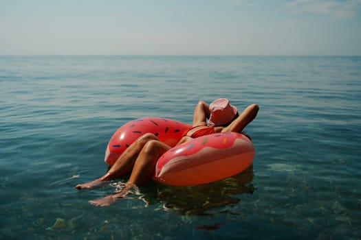 Summer vacation woman in hat floats on an inflatable donut mattress. Happy woman relaxing and enjoying family summer travel holidays travel on the sea