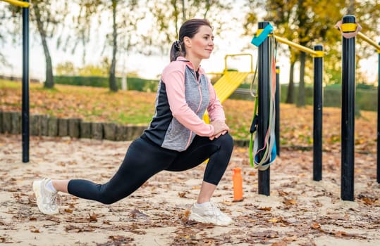 Fitness girl doing lunges outdoots in autumn time. Young woman exercising at nature in park