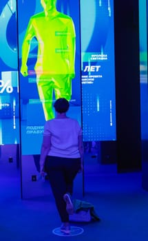 A woman performs exercises while looking at a huge monitor. Futuristic forum in Moscow. Moscow, Russia, August 19, 2023. High quality photo