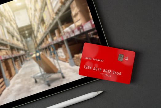 Red credit card on tablet with blurred market store on screen