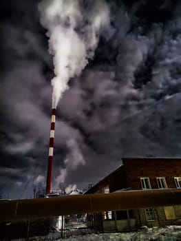 Winter night industrial landscape. Coal-fired power station with smoking chimneys against dramatic dark sky. Carbon dioxide CO2 emissions as primary driver of global climate change. Air pollution