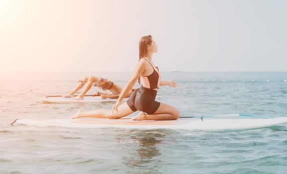 Woman man sup yoga. Happy young sporty couple practising yoga pilates on paddle sup surfboard. Female stretching doing workout on sea water. Modern family outdoor summer sport activity