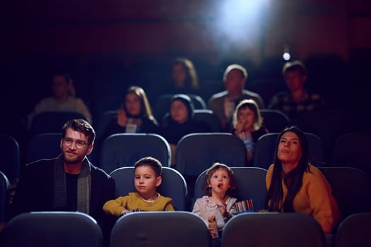 A modern family enjoys quality time together at the cinema, indulging in popcorn while watching a movie with their children.