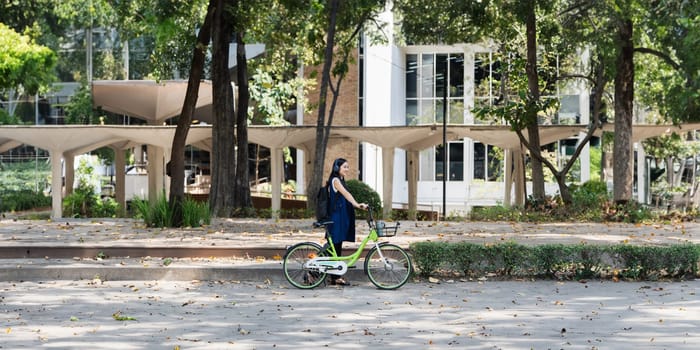 Asian young businesswoman bike to work for eco friendly green energy and listen music with headphone while commuting in city. Eco friendly.