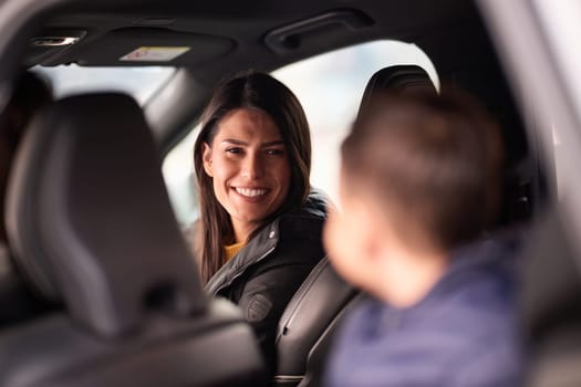 In the nighttime hours, a happy family enjoys playful moments together inside a car as they journey on a nocturnal road trip, illuminated by the glow of headlights and filled with laughter and joy.