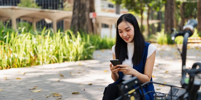 asian young businesswoman use smart phone while commuting in city. Eco friendly.