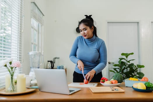 overweight Asian woman learning to make salad and healthy food from social media.