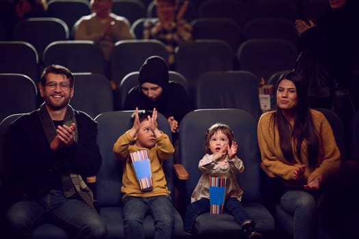 A modern family enjoys quality time together at the cinema, indulging in popcorn while watching a movie with their children.