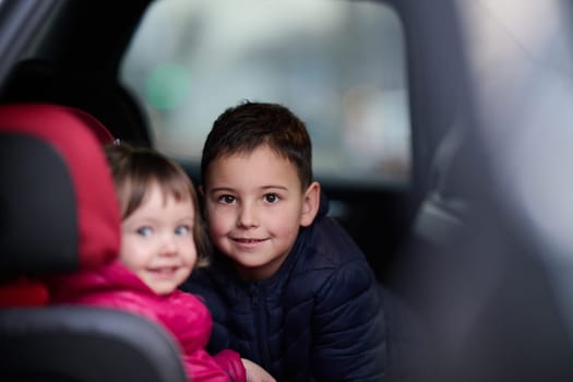 A young brother and sister enjoying a car ride together, immersed in the adventure of travel.