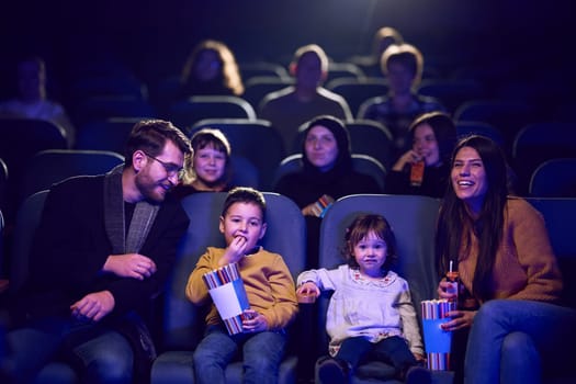 A modern family enjoys quality time together at the cinema, indulging in popcorn while watching a movie with their children.