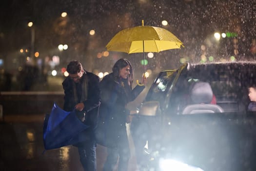 A family man lovingly opens the car for his family in rainy weather, sheltering them with an umbrella.